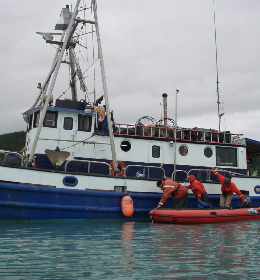 Men load inflatable boat next to tug