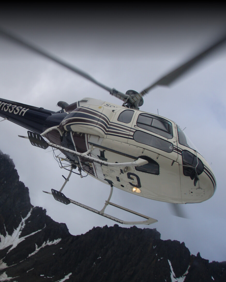 Helicopter flying over Alaskan mountains